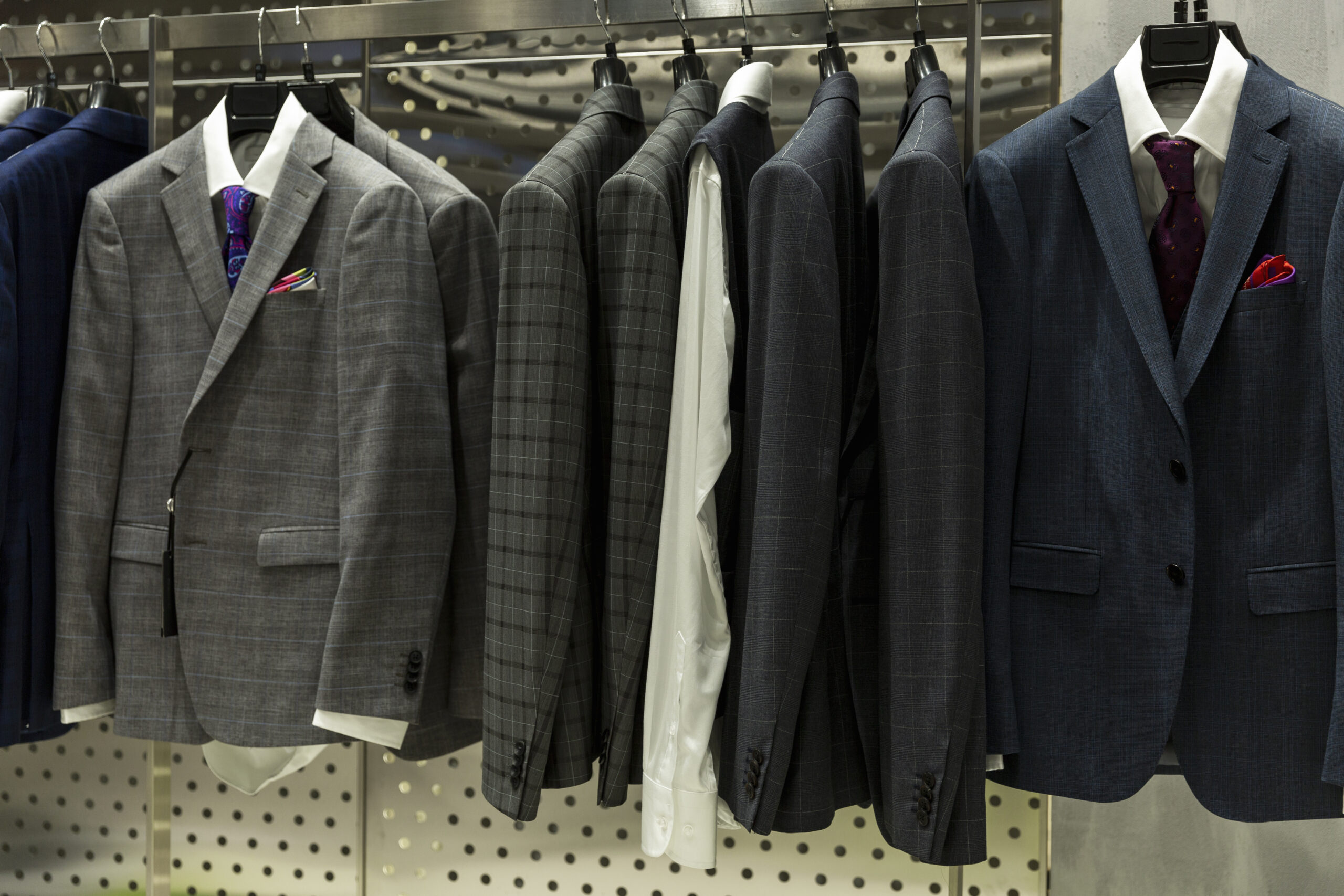 Stylish men's suits on hangers in the store. Front view. Eleganc